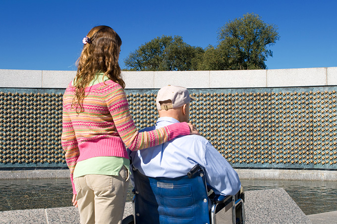 Hombre en silla de ruedas en el memorial con nieta