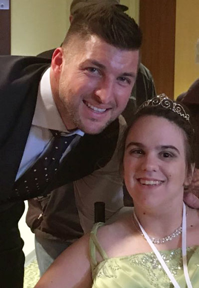 Tim Tebow posing with prom queen in wheelchair in green dress