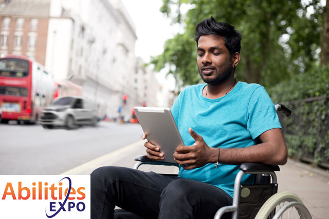 man in blue shirt in wheelchair looking at a tablet and the AbilitiesExpo logo