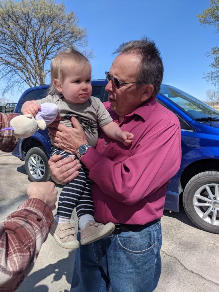 Man holds baby, standing in front of MobilityWorks rental van