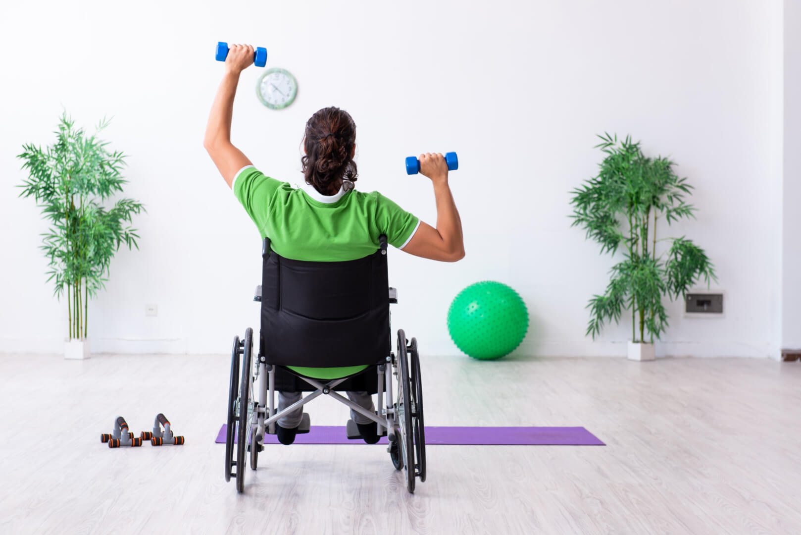 Young man in wheel-chair doing exercises indoors