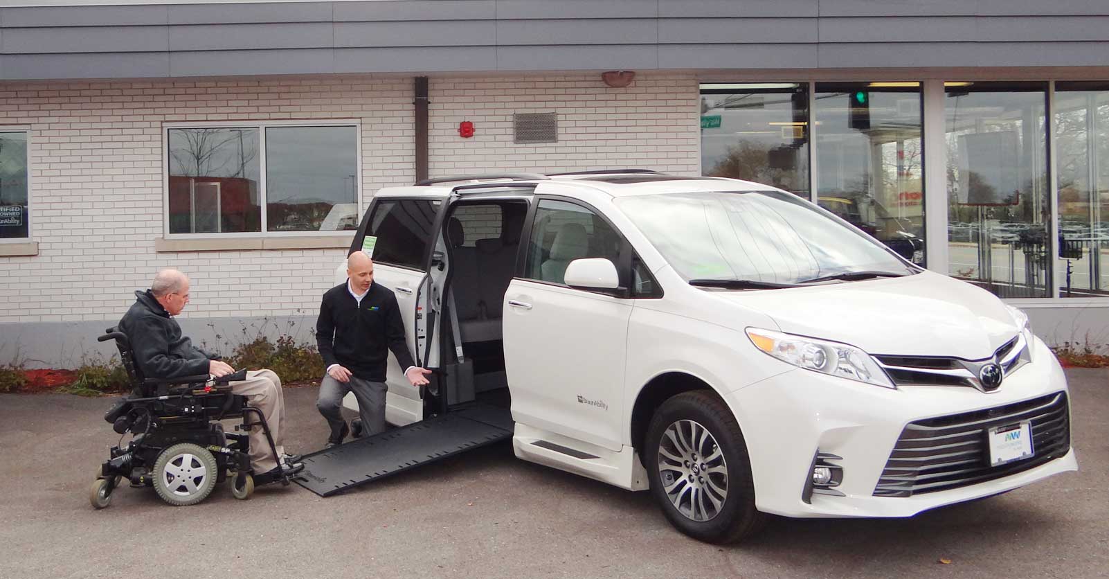 man in wheelchair rolling up ramp of white wheelchair van