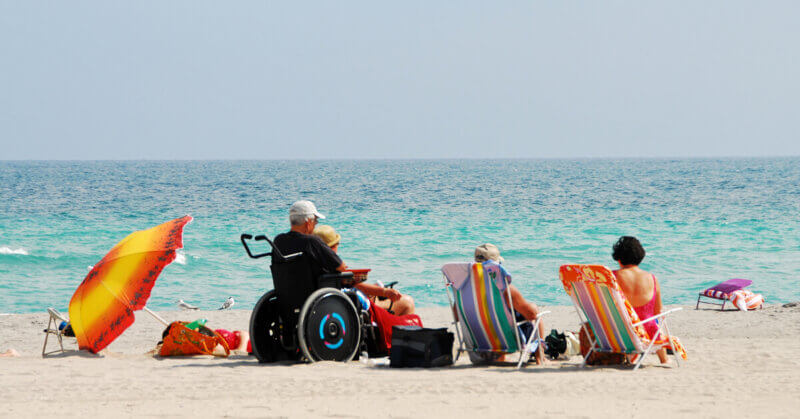 Grupo de personas en la playa uno en silla de ruedas