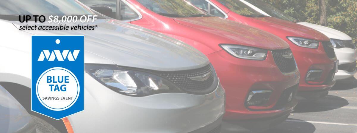 Row of parked accessible vehicles with a promotional badge showing up to $8,000 off select vehicles during the Blue Tag Savings Event.