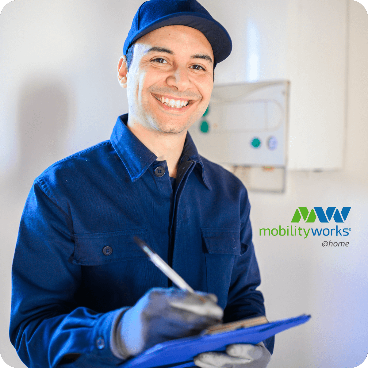 A smiling technician in a blue uniform and cap holds a clipboard and pen. The MobilityWorks @home logo and details about current MobilityWorks promotions are visible on the right side of the image.