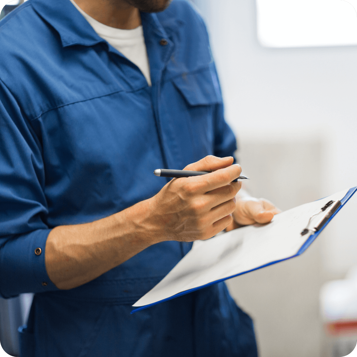 Person in a blue work uniform holding a clipboard and pen, appearing to take notes or conduct an inspection, possibly reviewing current MobilityWorks promotions.