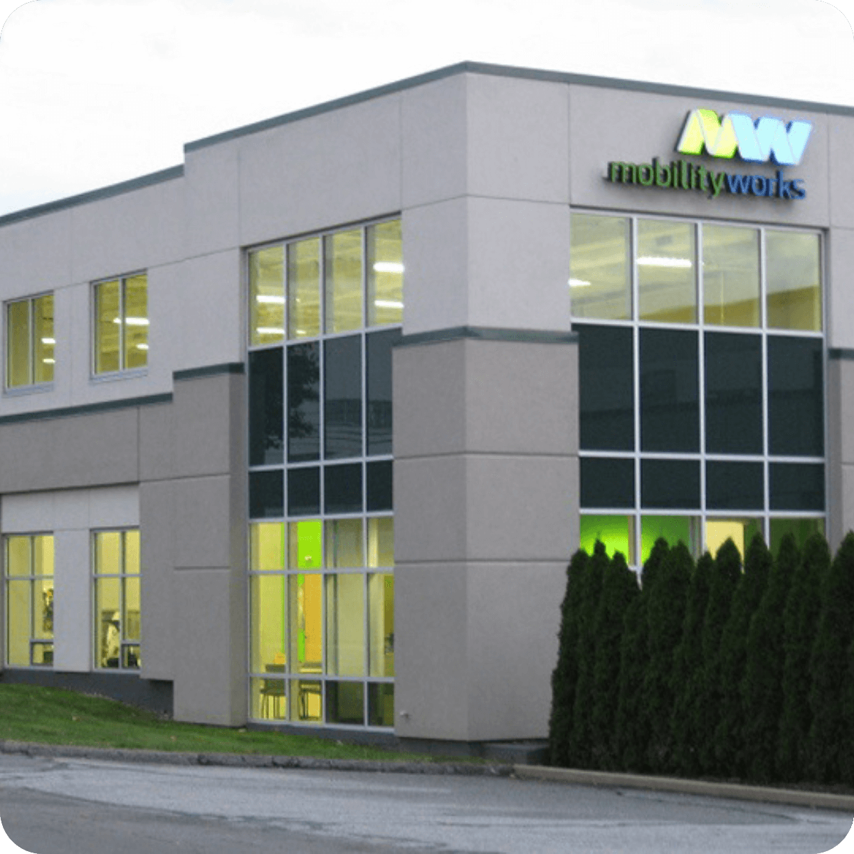 Modern two-story building with large windows and MobilityWorks signage on the exterior, surrounded by trimmed bushes and a paved driveway—perfect for exploring the latest MobilityWorks promotions.