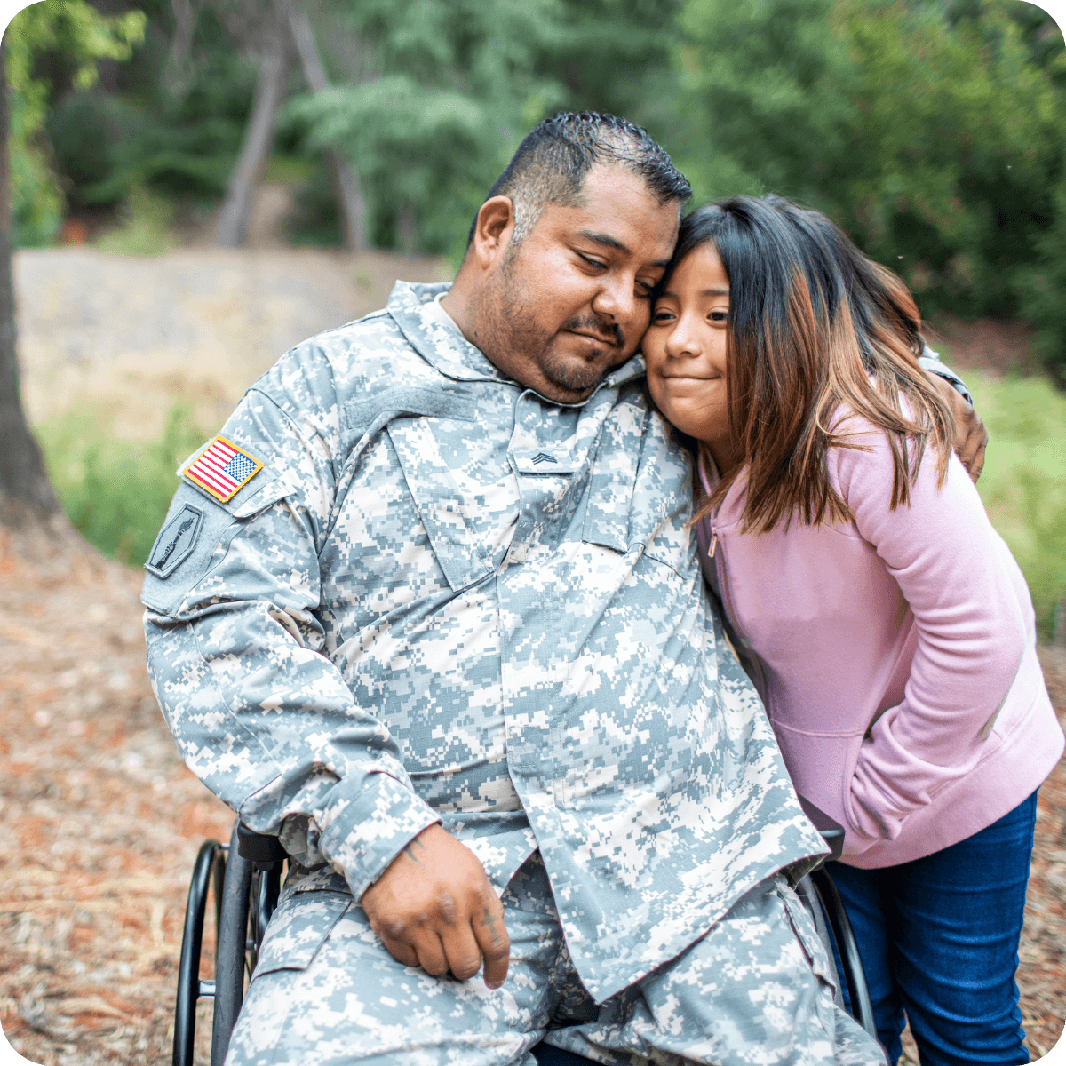 A man in military uniform sits in a wheelchair, hugging a young girl outdoors. Both look content and close, embodying the spirit of togetherness highlighted by MobilityWorks promotions.