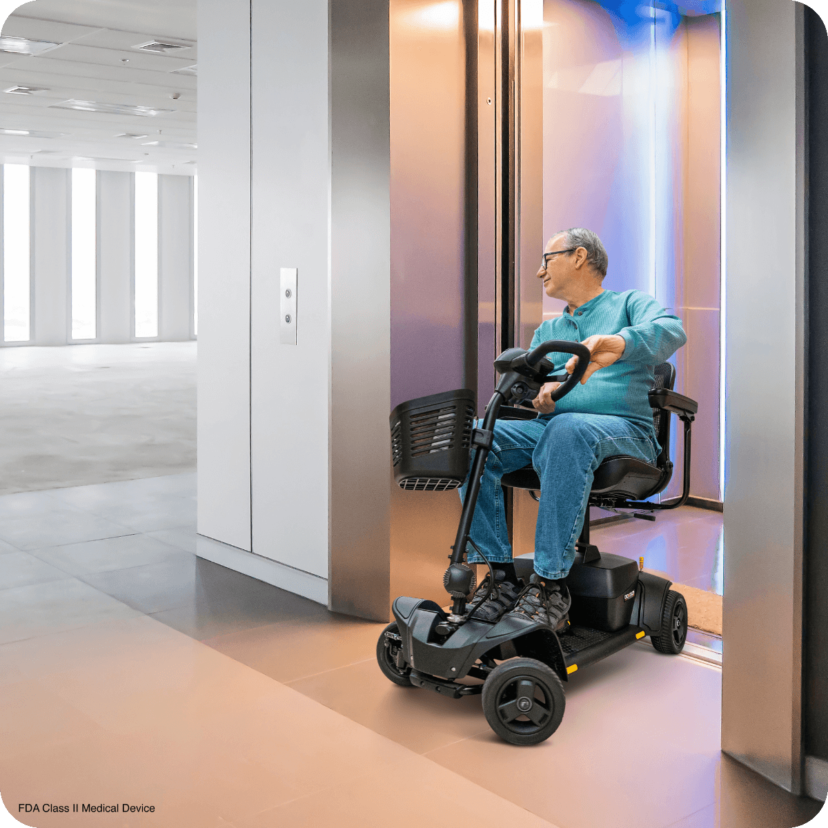 A man in a mobility scooter exits an elevator in a modern, spacious building with large windows and natural light.
