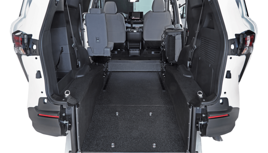 Interior view of a van with rear entry ramp, spacious floor, and seats positioned at the front, designed for wheelchair accessibility.