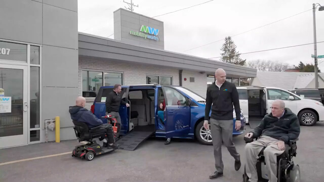 Los clientes de MobilityWorks observan los vehículos accesibles en el estacionamiento de la tienda