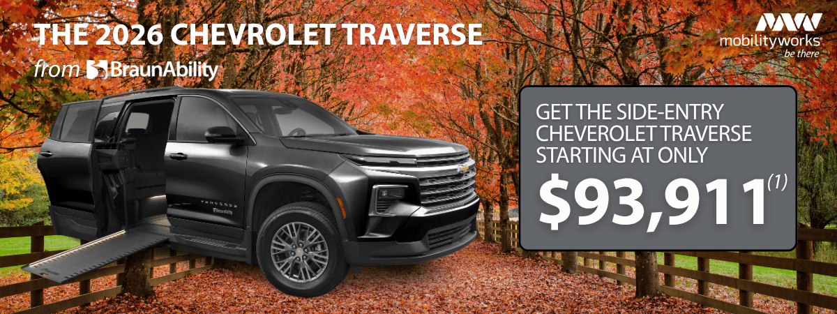 A black 2026 Chevrolet Traverse with a deployed side-entry ramp is parked on a wooden bridge amid autumn trees. Price and MobilityWorks promotions appear on the right.
