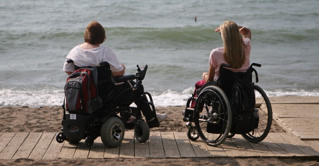 Two wheelchair users on beach boardwalk