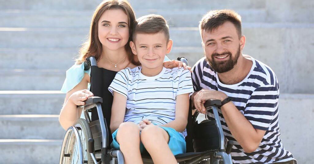 Teenage boy in wheelchair with his parents outdoors