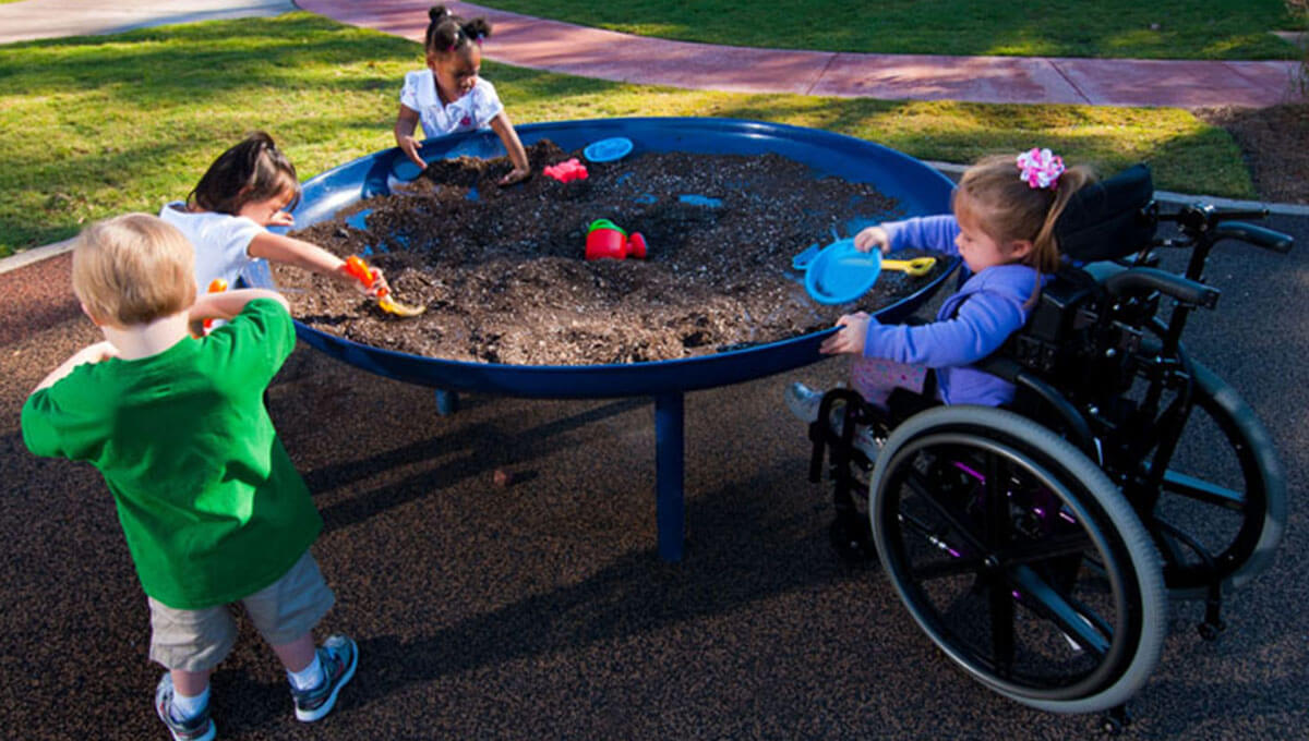 Los niños juegan en una mesa de arena elevada.