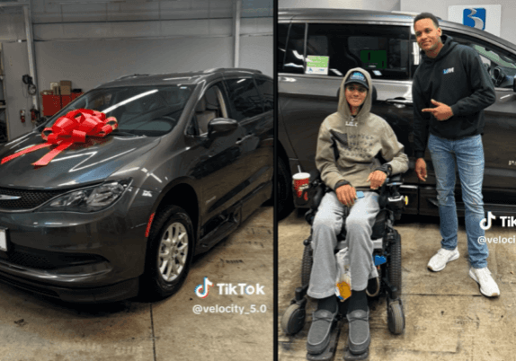 A man in a wheelchair poses with another man beside a minivan adorned with a red bow inside a garage.