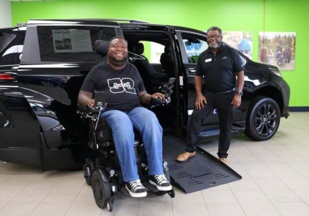 Eric LeGrand in front of a wheelchair accessible vehicle.