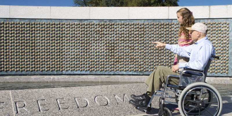 Abuelo en silla de ruedas con nieta en el Memorial de la Segunda Guerra Mundial