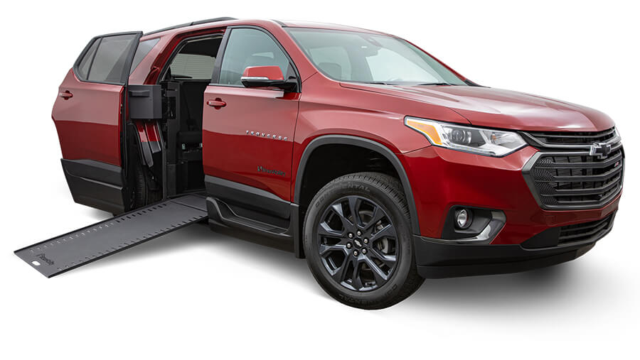 Red Chevorlet Traverse with left side sliding door open and a wheelchair ramp leading inside