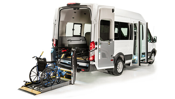 White commercial van with an open passenger seat door and a wheelchair lift leading into the rear doorway