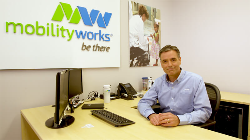 customer-service-banner man in MobilityWorks shirt sitting at a desk