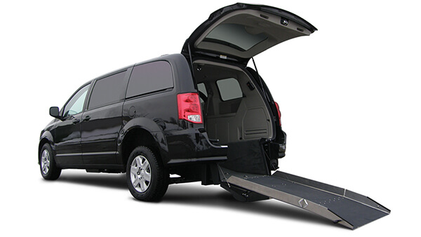 La parte trasera de una camioneta Braunability negra con un maletero abierto y una rampa para sillas de ruedas que se extiende hasta el suelo