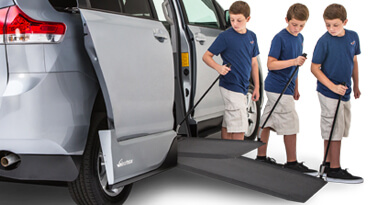Boy setting ramp down ramp on a wheelchair van 