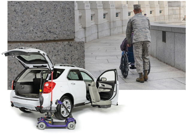 White SUV with scooter lift and turning seat in front of veteran pushing person in wheelchair at war memorial