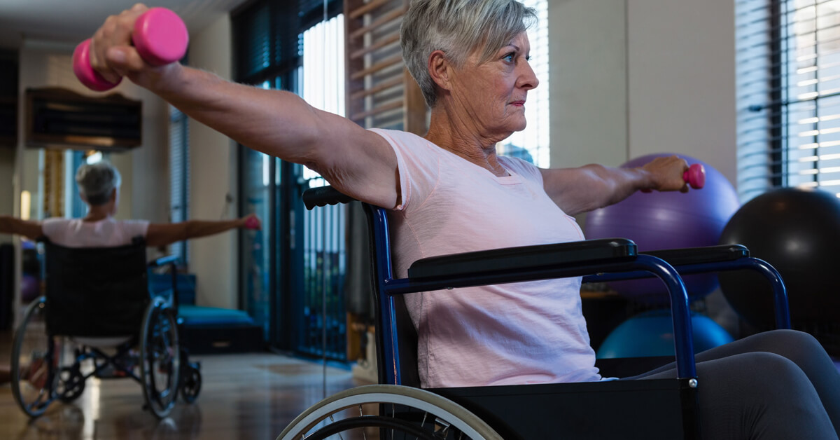 Mujer Senior en silla de ruedas realizando ejercicios con mancuernas