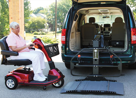 Mujer en scooter rojo junto a la plataforma elevadora extendida al suelo desde la parte trasera del vehículo