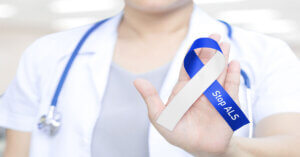 Doctor in white uniform with stethoscope holding ribbon with text Stop ALS