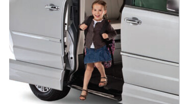 Little schoolgirl stepping out of a wheelchair van 