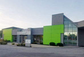 Grey and green building with glare in window during sunset