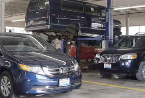 A blue Honda, commercial van, and SUV in a garage