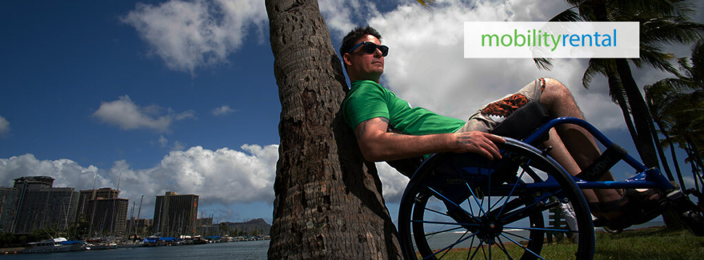 A man using a wheelchair enjoys a sunny outdoor moment, with 'MobilityRental' branding visible in the top right corner.