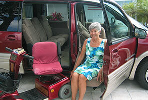 woman using a turning seat to exit vehicle with scooter next to her.