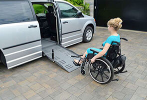 woman in wheelchair using a powerpull ramp assistant to enter a wheelchair van with a side entry ramp